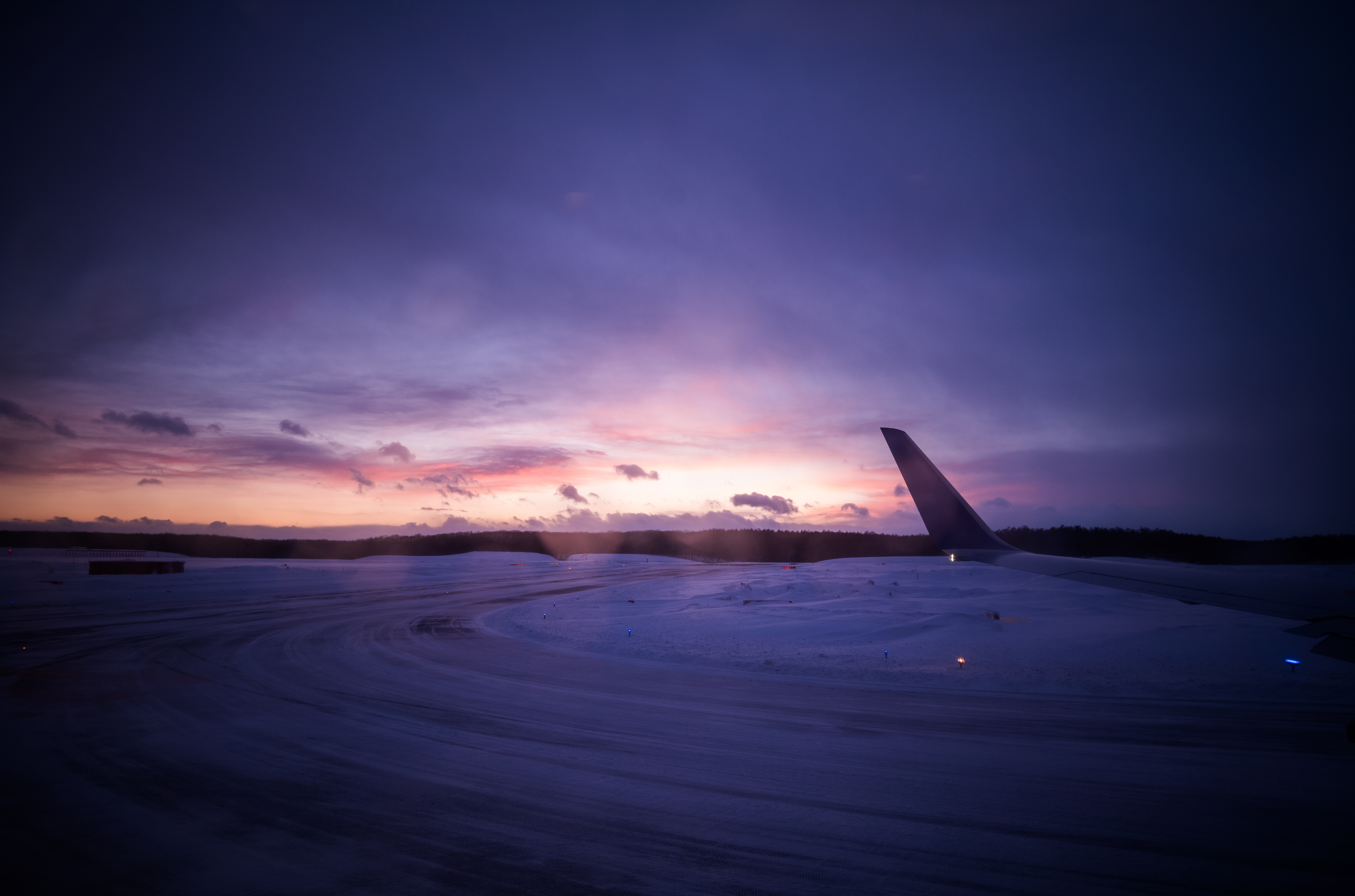 Runway - 冬の千歳空港でカーブを描く滑走路と、雲の隙間から漏れる夕暮れ。